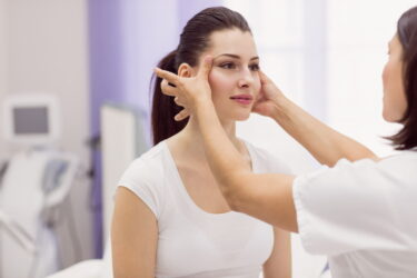 Dermatologist examining female patient skin in clinic