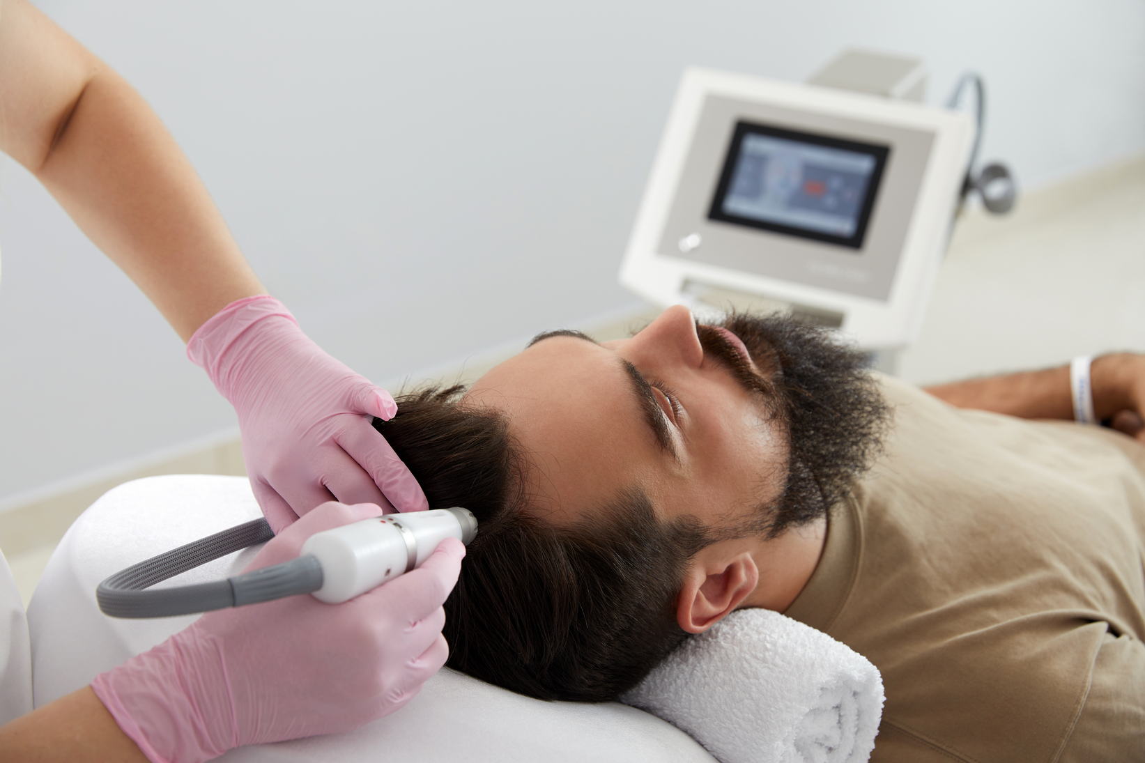 Doctor female dermatologist trichologist makes a procedure to stimulate hair growth on head to a patient man