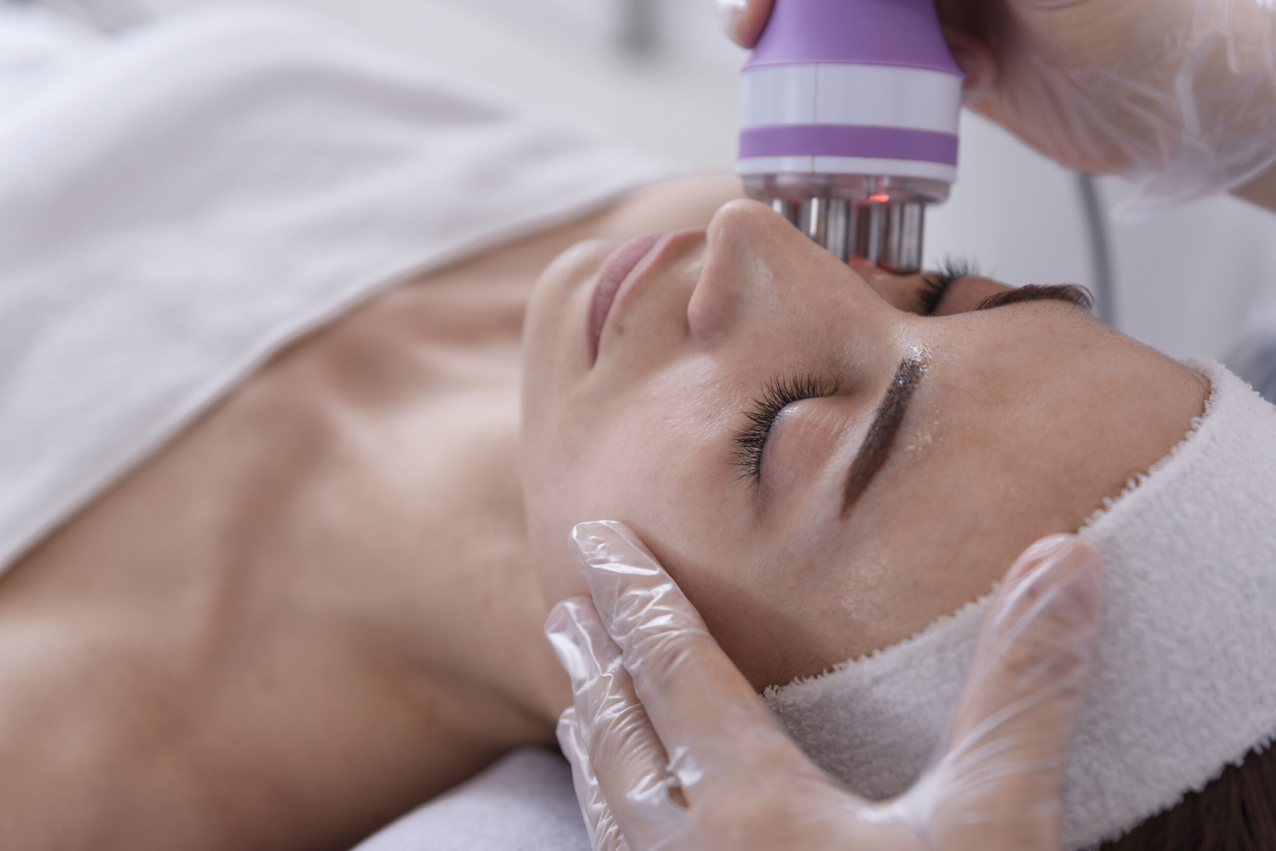 A young woman undergoing a facial radiofrequency face lift treatment. Facial skin care treatment, anti-aging facial rejuvenation. Beauty and dermatology concept.